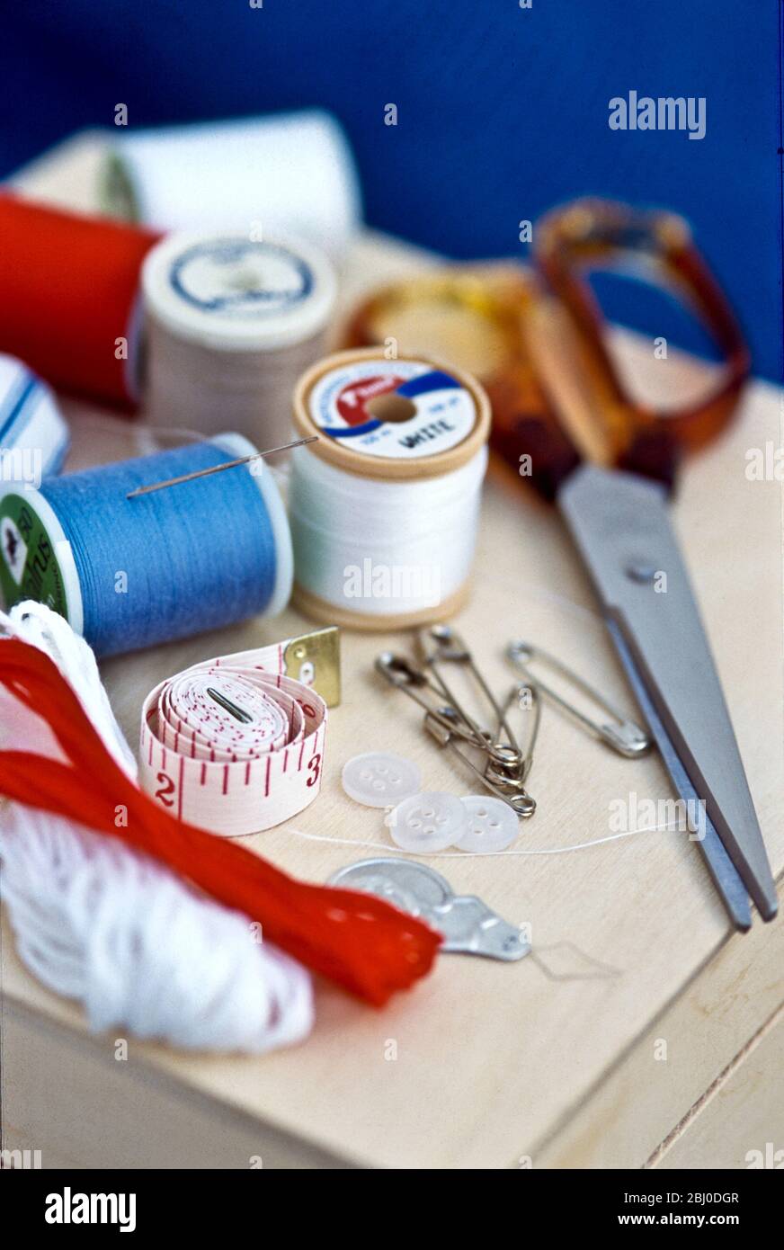 Vari pezzi di kit per cucire, compresi fili, aghi e forbici su scatola di legno. - Foto Stock