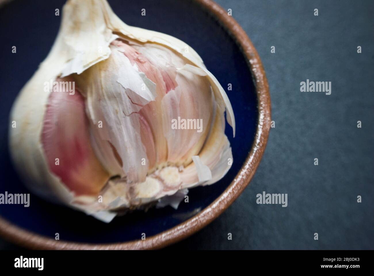 Bulbo singolo di aglio rotto aperto in ciotola piccola - Foto Stock