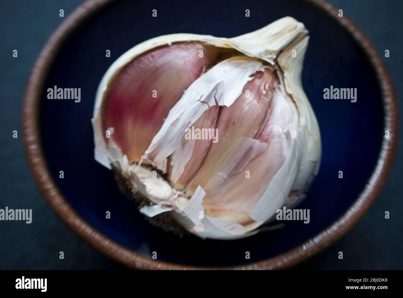 Bulbo singolo di aglio rotto aperto in ciotola piccola - Foto Stock