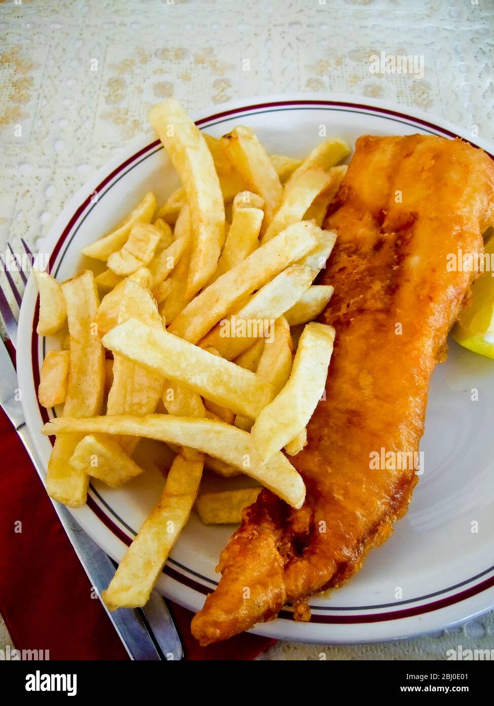 Pesce britannico classico e patatine fritte al tavolo in ristorante tipico. - Foto Stock