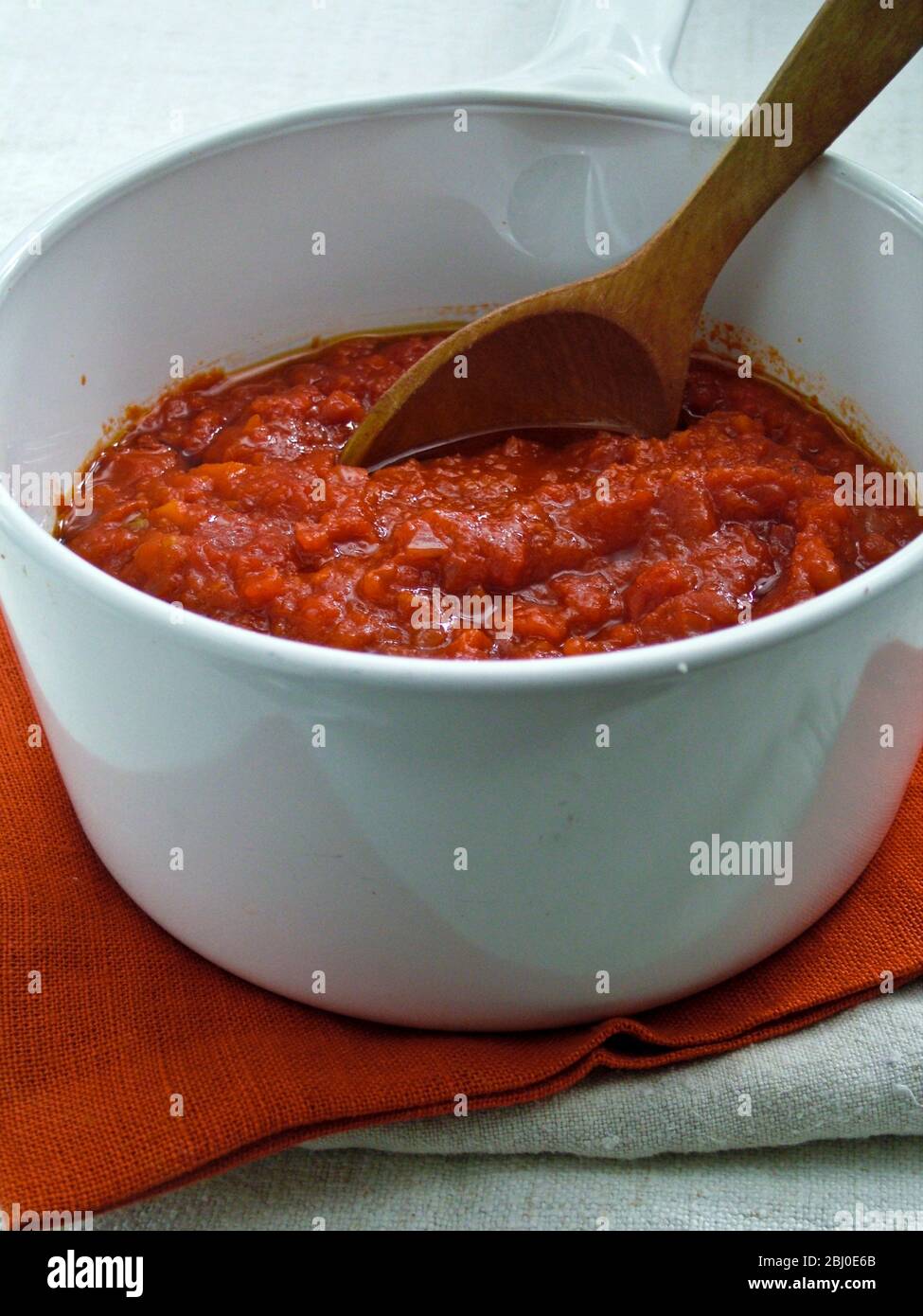 Preparare il salsa di tonato in una pentola bianca in ceramica, mescolando con un cucchiaio di legno - Foto Stock