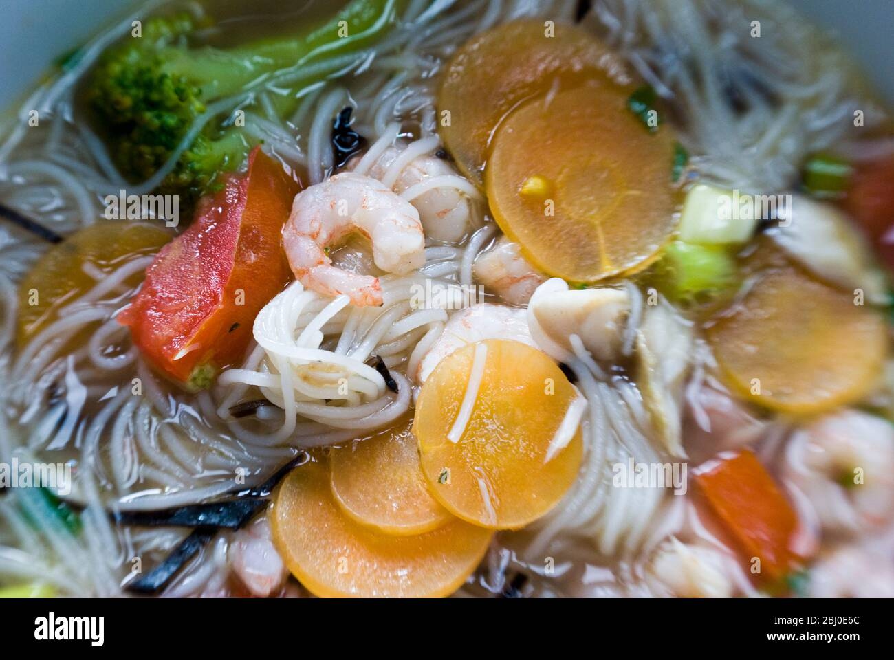 Ciotola di zuppa di stile asiatico con tagliatelle di riso, gamberi e verdure - Foto Stock