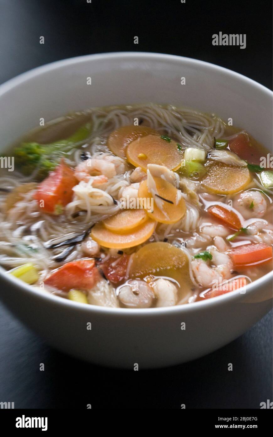 Ciotola di zuppa di stile asiatico con tagliatelle di riso, gamberi e verdure - Foto Stock