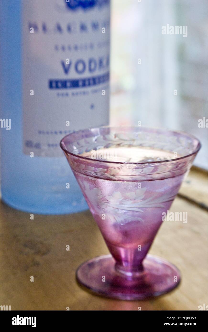 Piccolo vetro decorativo di vodka sulle rocce, su vassoio di foglie d'oro, con bottiglia di vodka Blackwood Shetland filtrata a freddo - Foto Stock