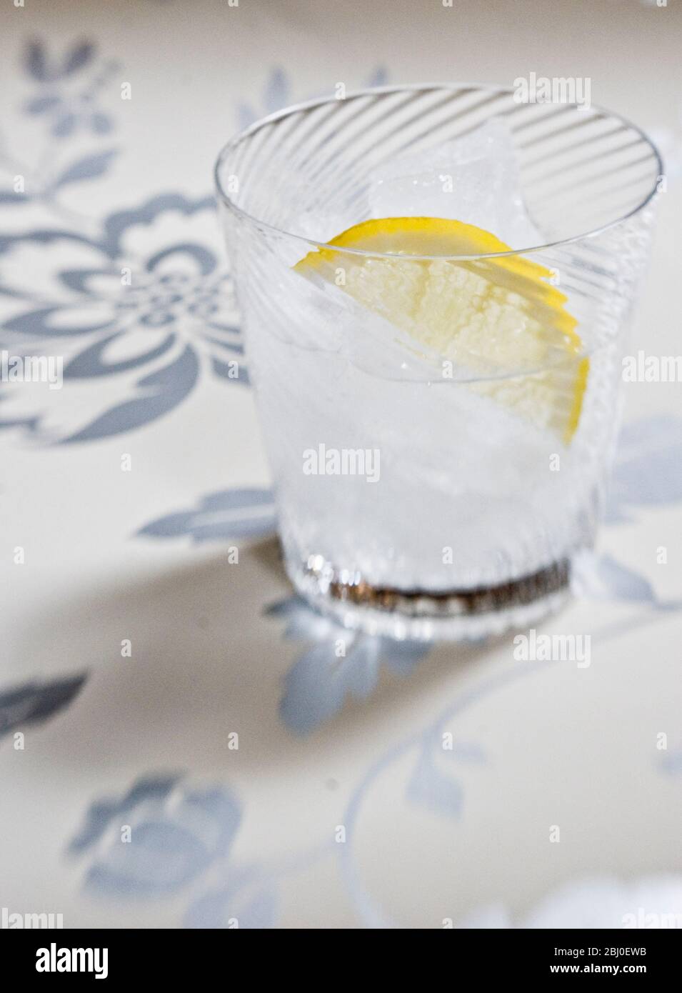 Vetro soffiato a spirale fine di spirito chiaro con soda o tonico, e fetta di limone su sfondo decorativo - Foto Stock