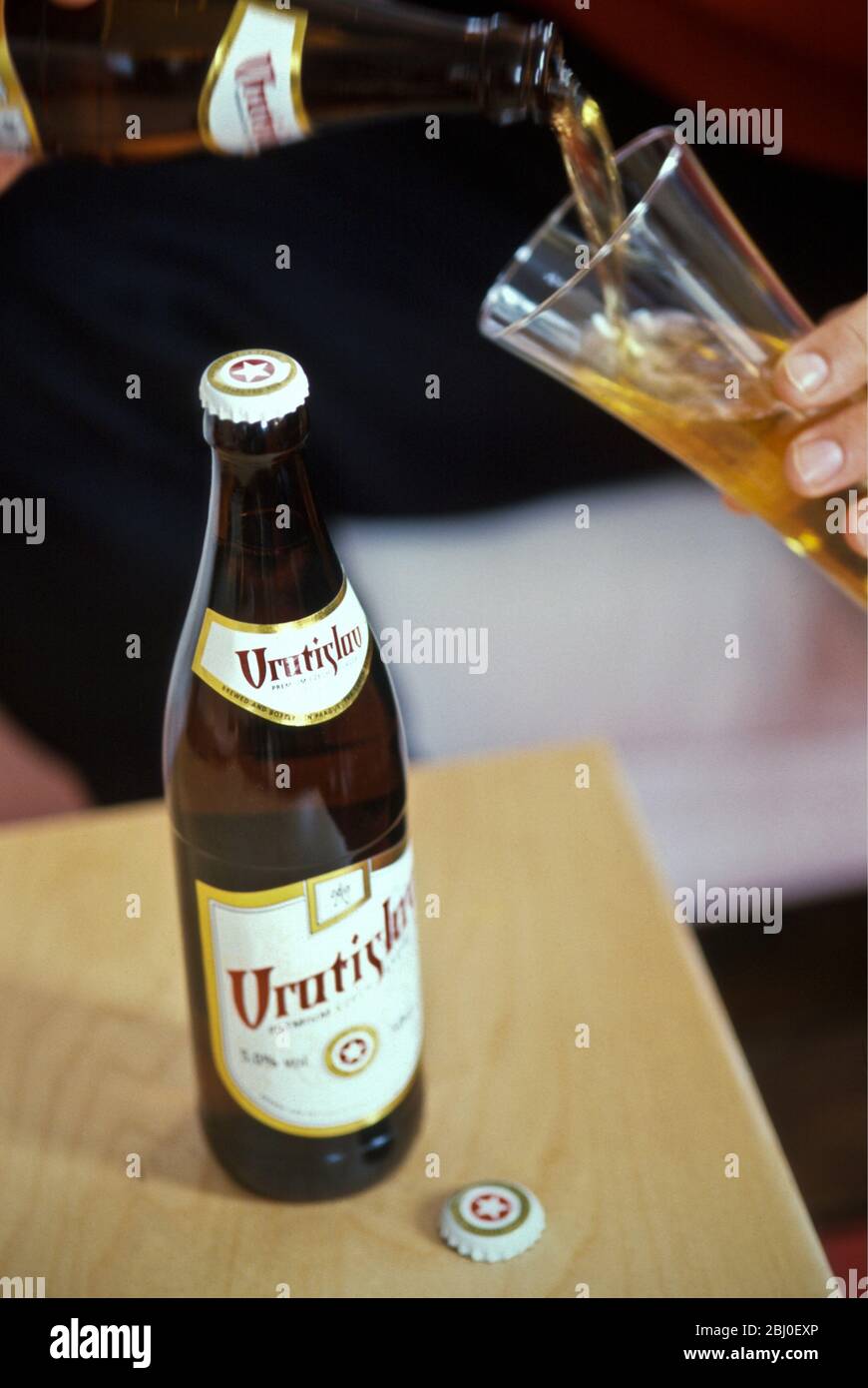 Versare la birra ceca in un bicchiere alto. - Foto Stock