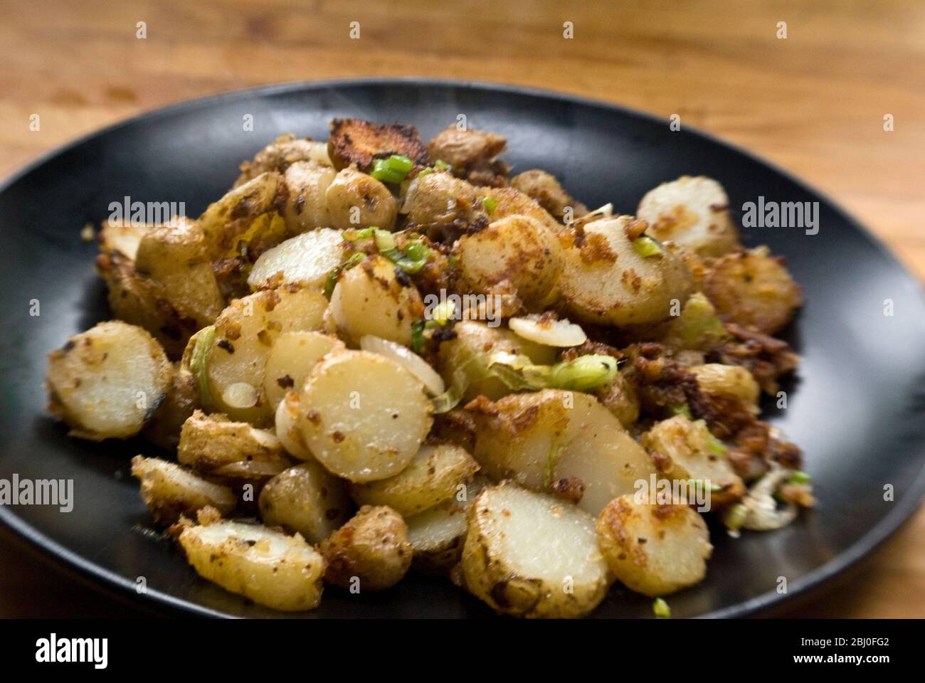 Piatto di patate fritte, saltati con acciughe, cipolle primaverili e pangrattato. - Foto Stock