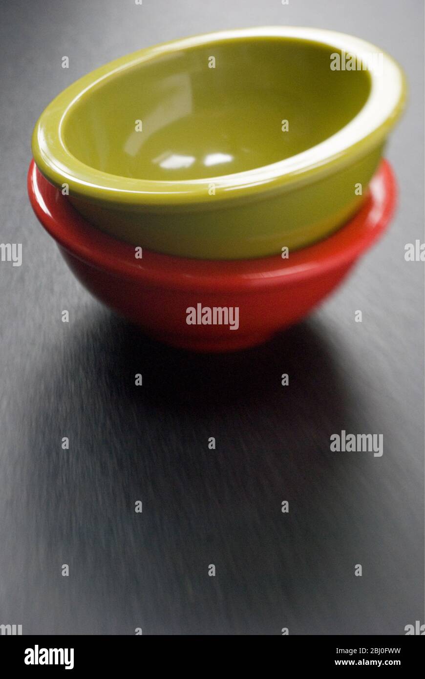 Due bowl di melammina brillanti impilati su superficie scura - Foto Stock