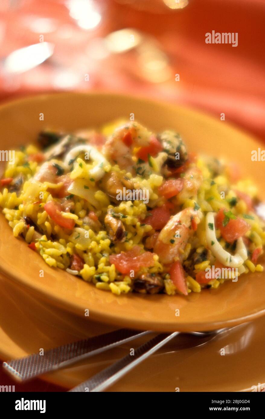 Paella gialla zafferano su piatto giallo ocra. - Foto Stock