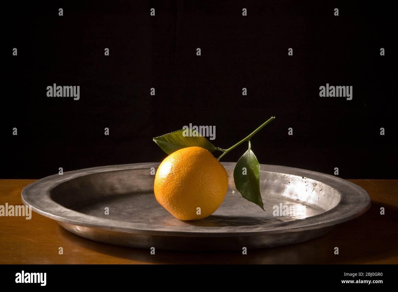Arancione con foglie sul caricabatterie peltro - Foto Stock