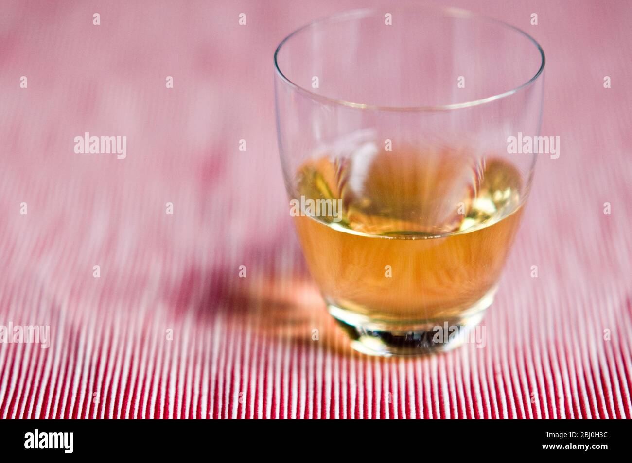Moderno bicchiere di Scotch whisky e acqua su sfondo rosso a strisce - Foto Stock
