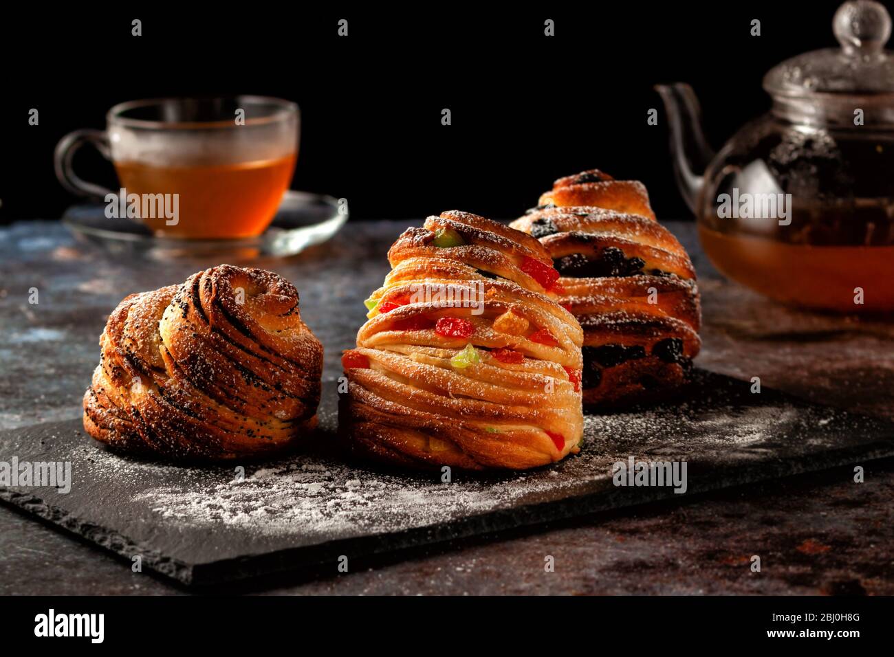 Krafins con uvetta, frutta candita e semi di papavero, cosparsi di zucchero in polvere. Foto Stock