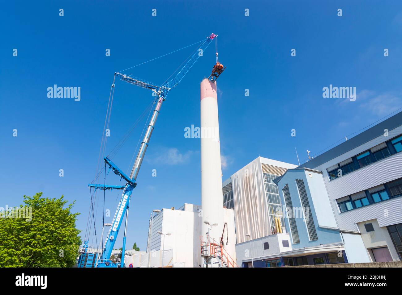 Vienna: Demolizione del camino dell'impianto di riscaldamento urbano di Kagran che non è più utilizzato con un 'escavatore volante'. Le macerie finiscono in essi Foto Stock
