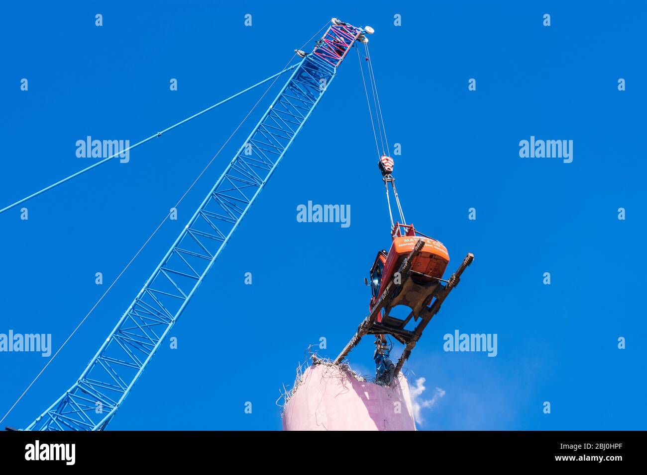 Vienna: Demolizione del camino dell'impianto di riscaldamento urbano di Kagran che non è più utilizzato con un 'escavatore volante'. Le macerie finiscono in essi Foto Stock