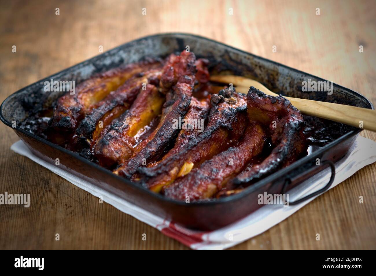 Costine di maiale al forno e appiccicose in lattina di cottura in metallo vecchio - Foto Stock