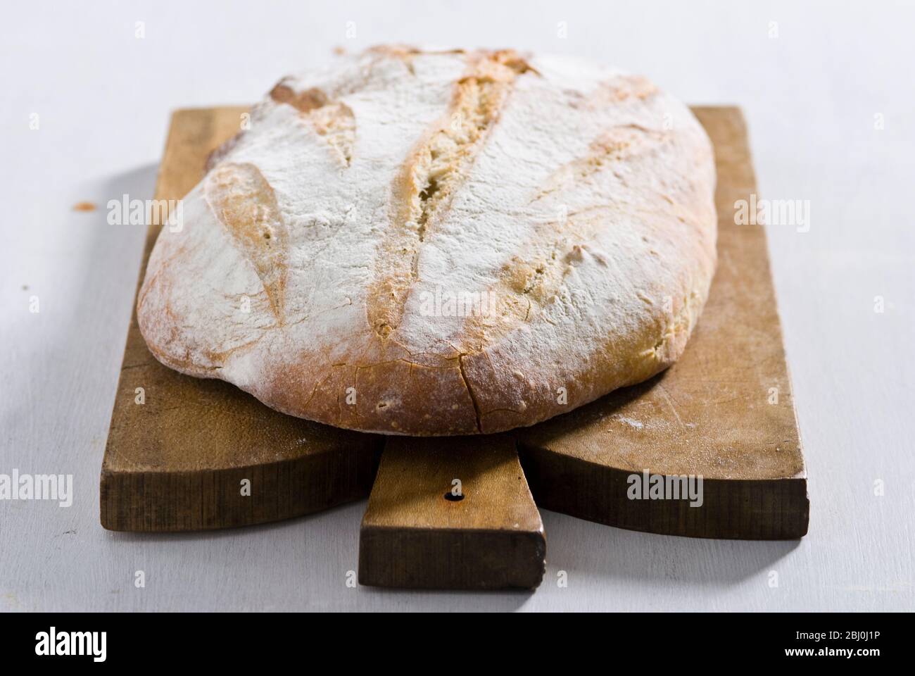 Pane bianco rustico biologico su tagliere in legno - Foto Stock