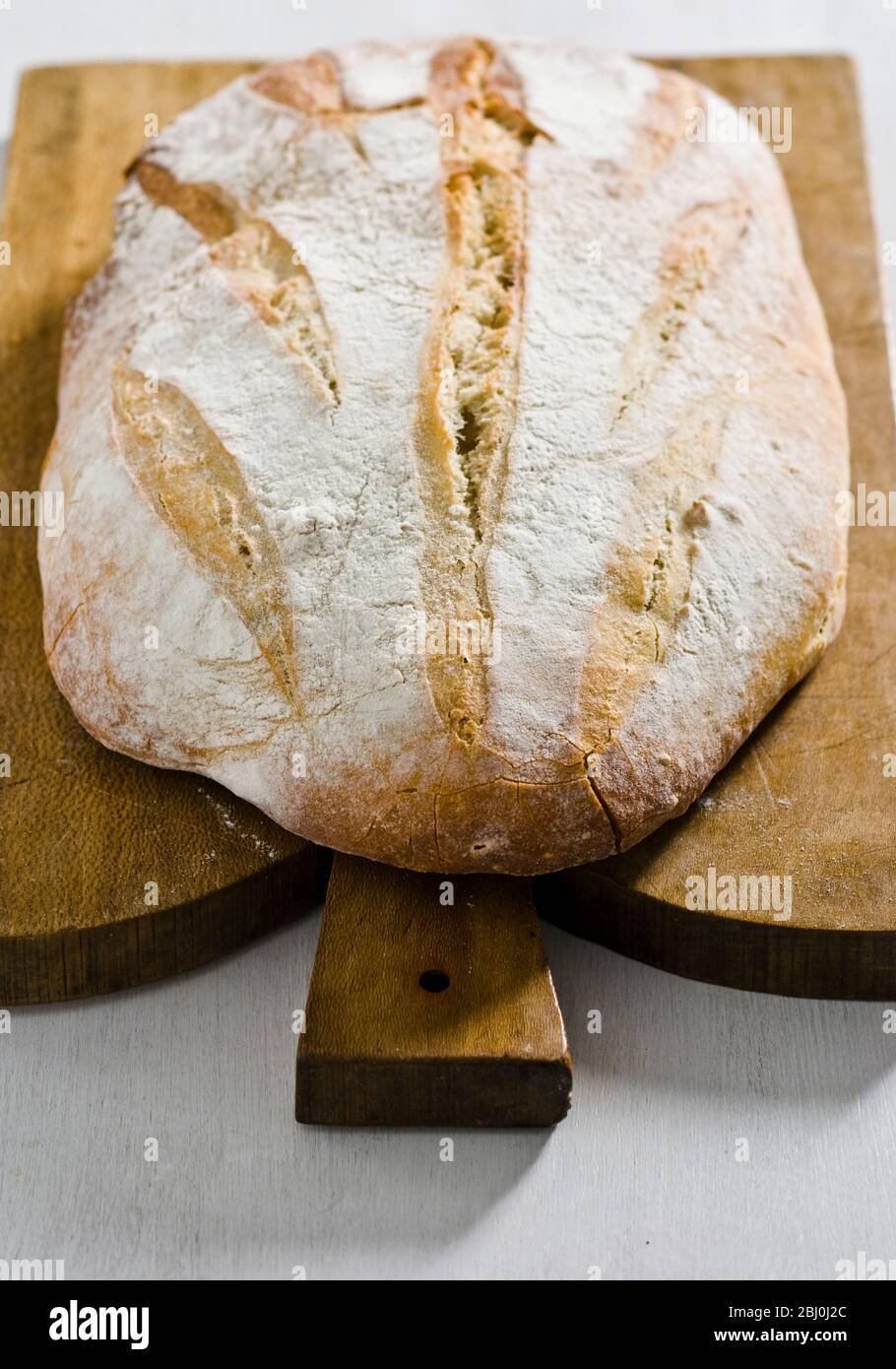 Pane bianco rustico biologico su tagliere in legno - Foto Stock