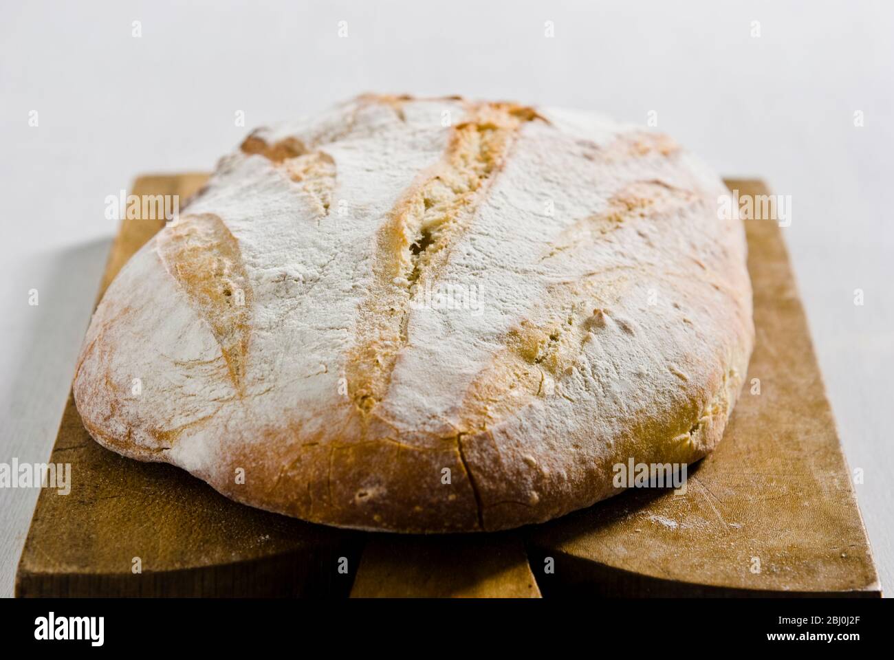 Pane bianco rustico biologico su tagliere in legno - Foto Stock