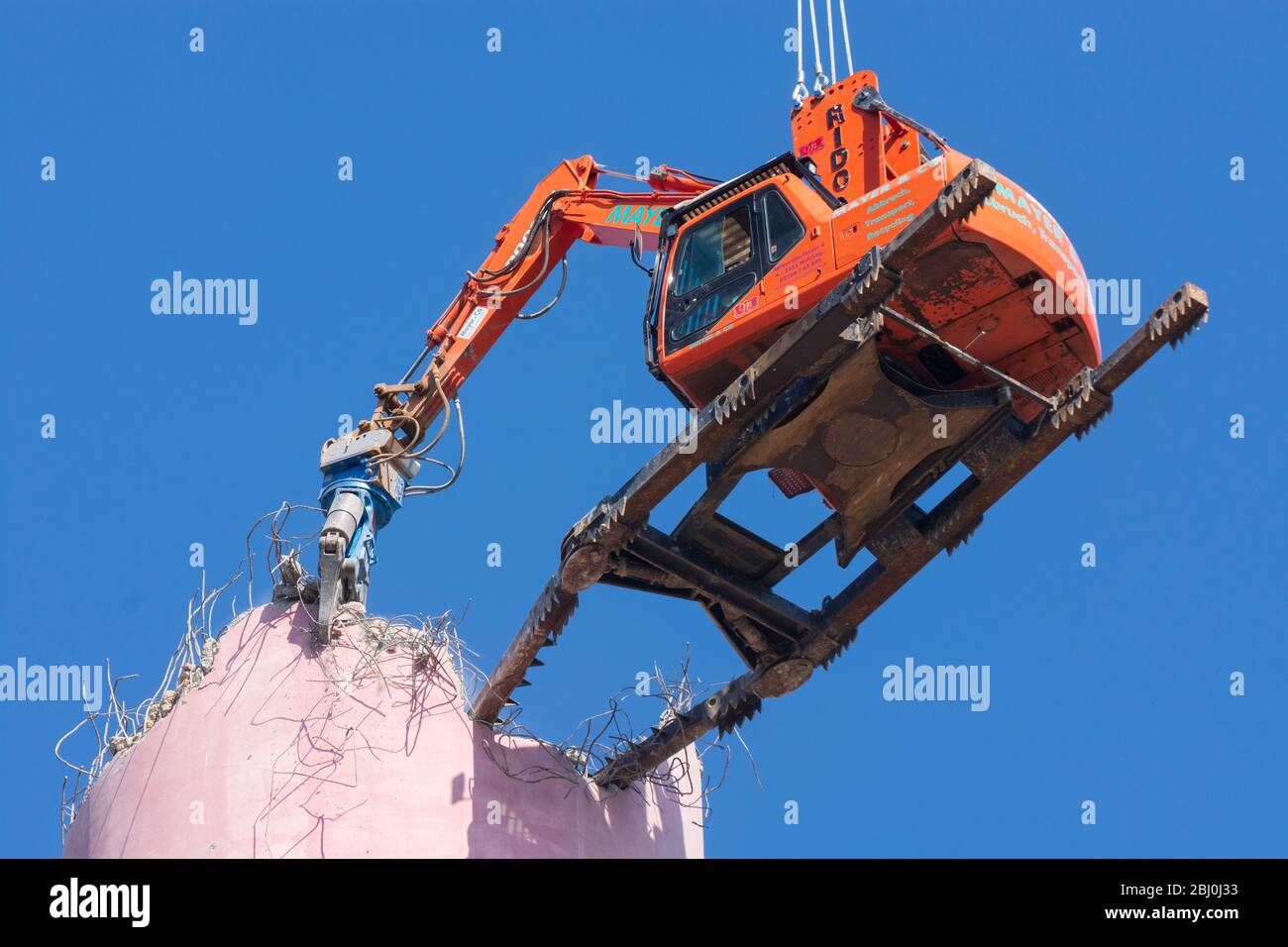 Vienna: Demolizione del camino dell'impianto di riscaldamento urbano di Kagran che non è più utilizzato con un 'escavatore volante'. Le macerie finiscono in essi Foto Stock