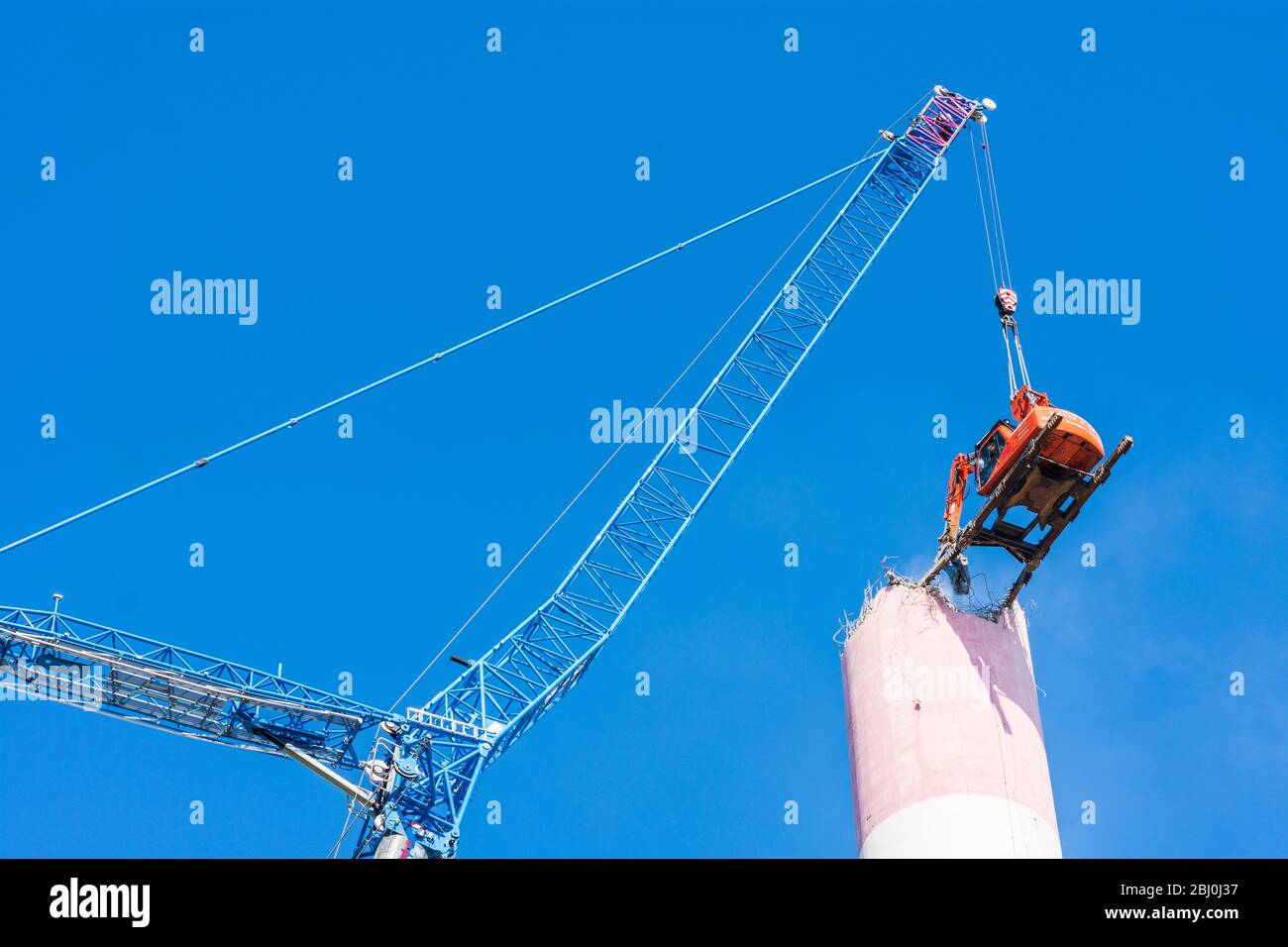 Vienna: Demolizione del camino dell'impianto di riscaldamento urbano di Kagran che non è più utilizzato con un 'escavatore volante'. Le macerie finiscono in essi Foto Stock