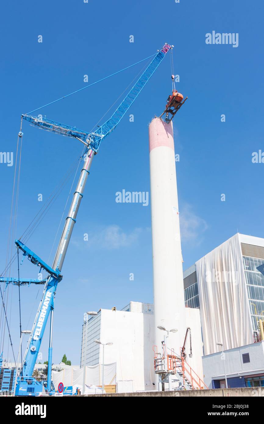 Vienna: Demolizione del camino dell'impianto di riscaldamento urbano di Kagran che non è più utilizzato con un 'escavatore volante'. Le macerie finiscono in essi Foto Stock