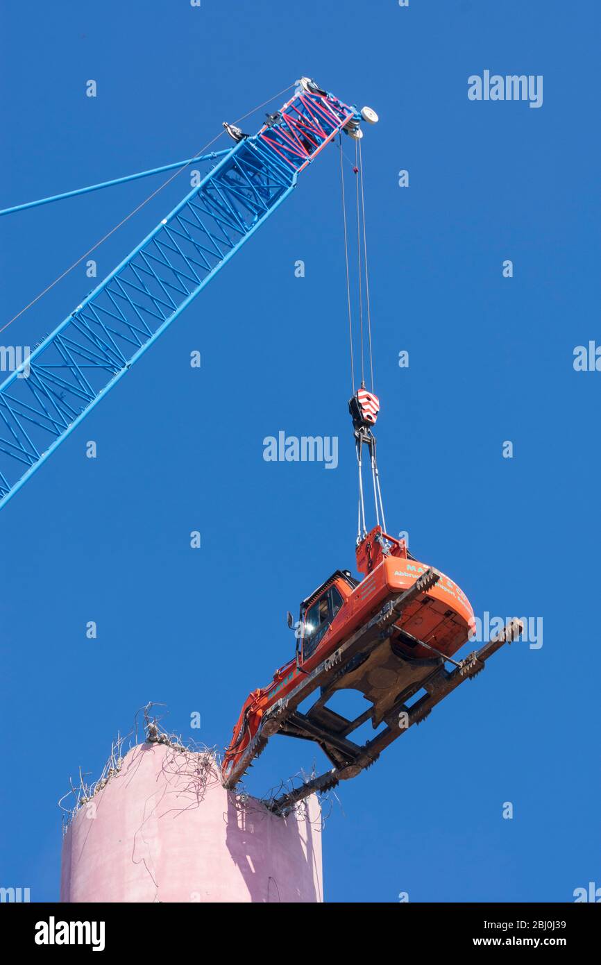Vienna: Demolizione del camino dell'impianto di riscaldamento urbano di Kagran che non è più utilizzato con un 'escavatore volante'. Le macerie finiscono in essi Foto Stock
