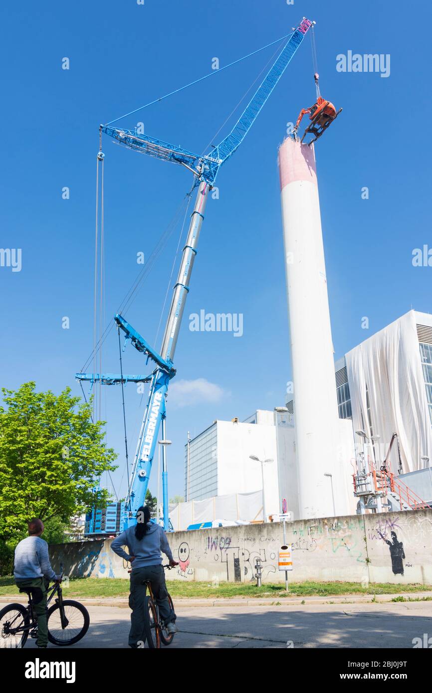 Vienna: Demolizione del camino dell'impianto di riscaldamento urbano di Kagran che non è più utilizzato con un 'escavatore volante'. Le macerie finiscono in essi Foto Stock
