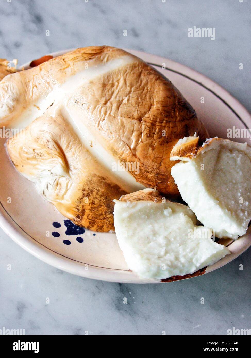 Mozzarella di bufala fresca affumicata su piatto Ialian su bancone in marmo Foto Stock