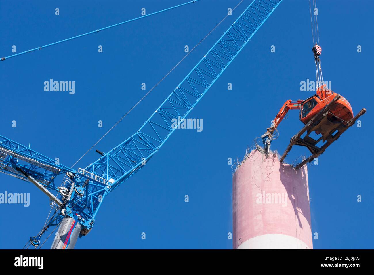 Vienna: Demolizione del camino dell'impianto di riscaldamento urbano di Kagran che non è più utilizzato con un 'escavatore volante'. Le macerie finiscono in essi Foto Stock