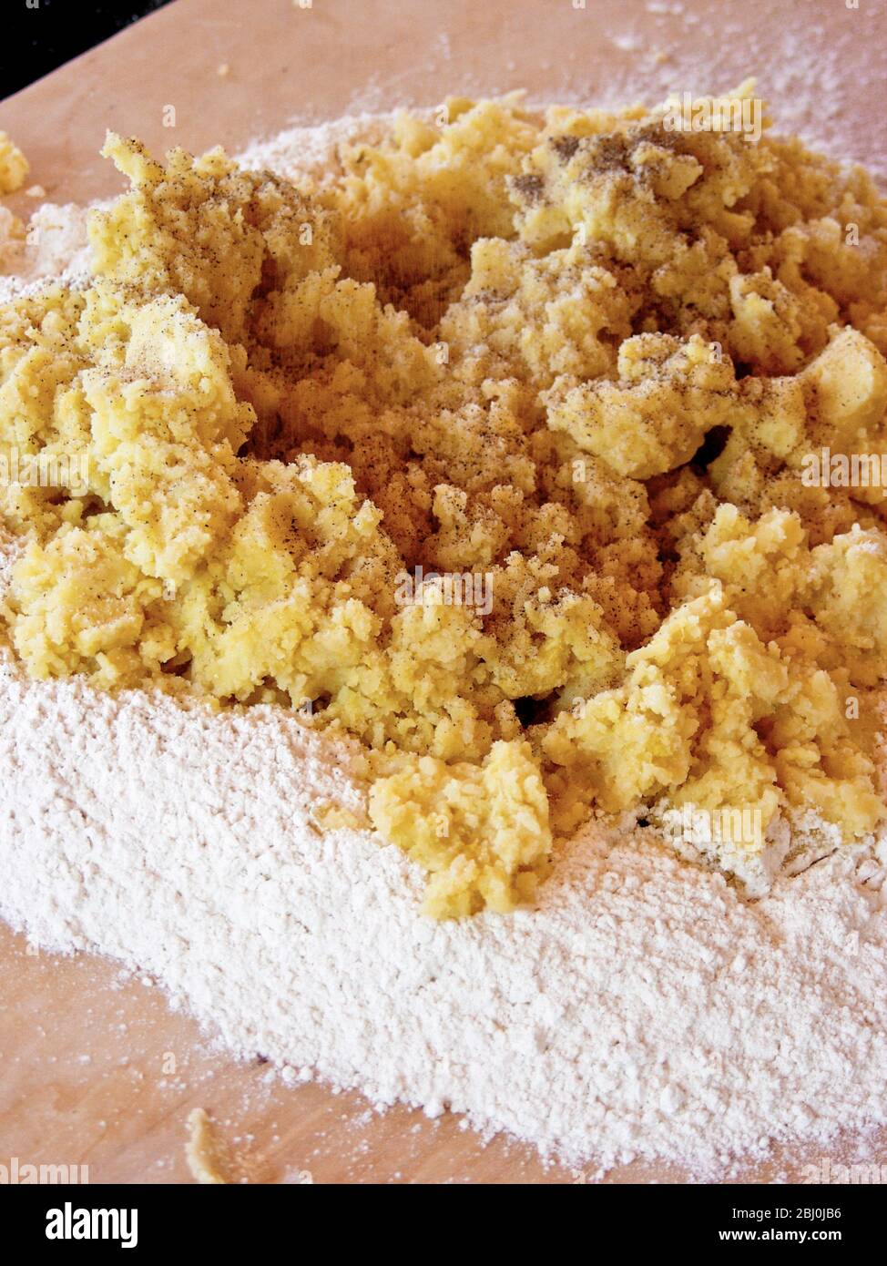 Mescolando patate pressate e parmigiano grattugiato in farina per produrre gnocchi. Foto Stock