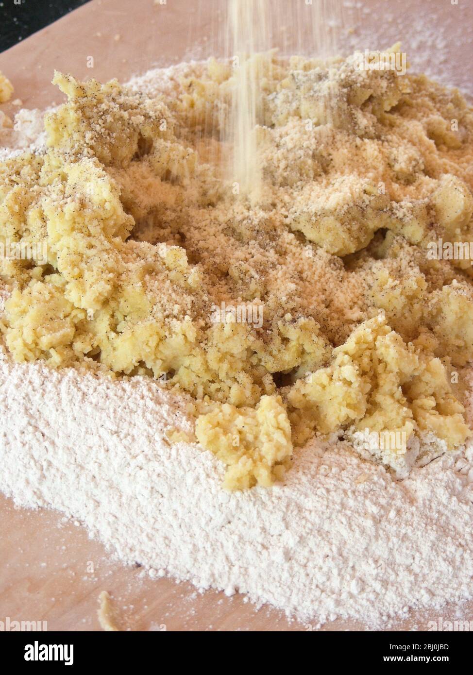 Mescolando patate pressate e parmigiano grattugiato in farina per produrre gnocchi. Foto Stock