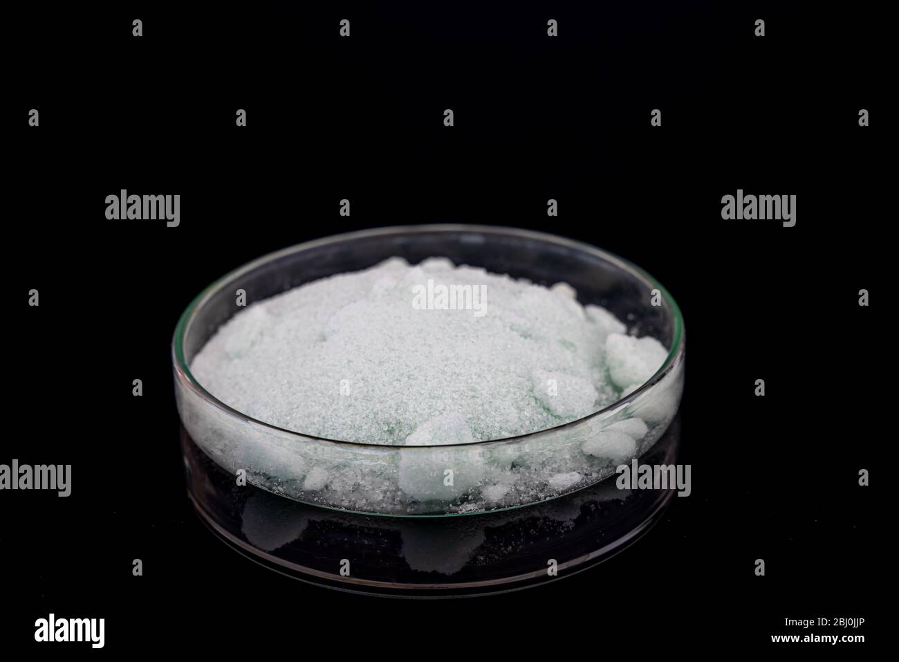 Solfato di ferro(II) di ammonio, o sale di Mohr in piastra Petri su sfondo nero Foto Stock