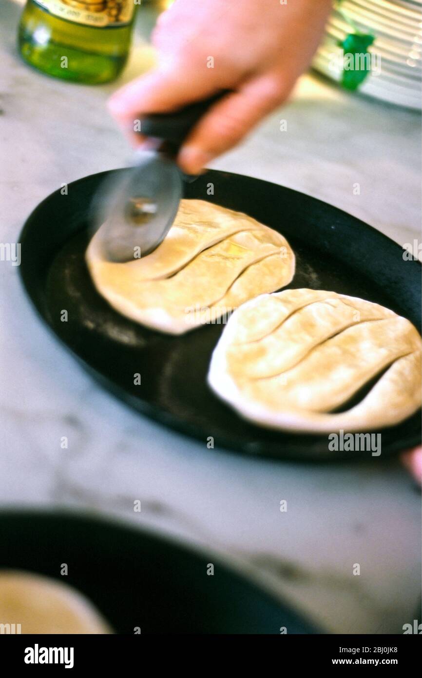 Pasta per pizza arrotolata con olio d'oliva tagliato in forma prima di cuocere come focaccia - Foto Stock
