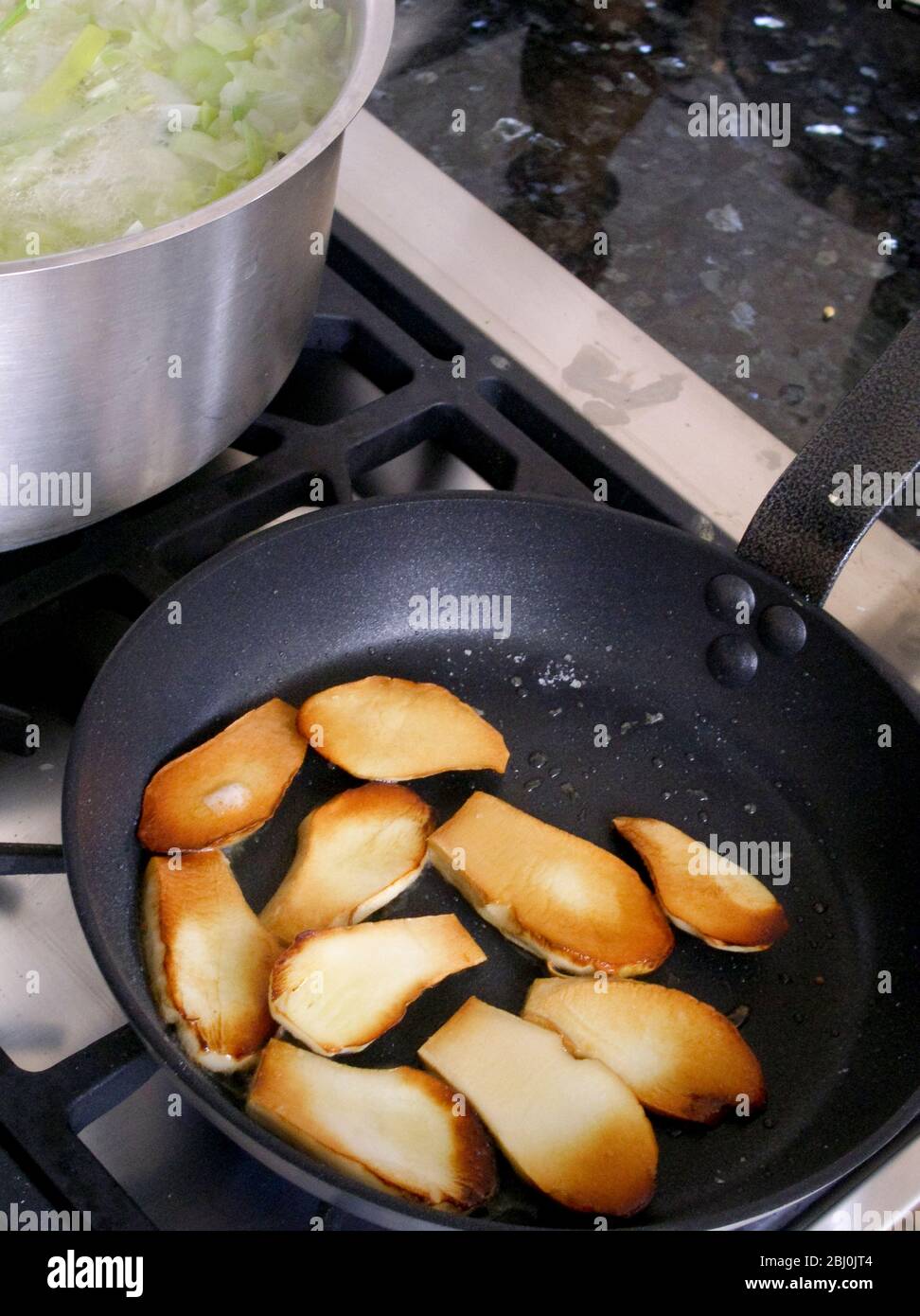 Fette di ciepoli fritte rapidamente in olio d'oliva caldo. - Foto Stock