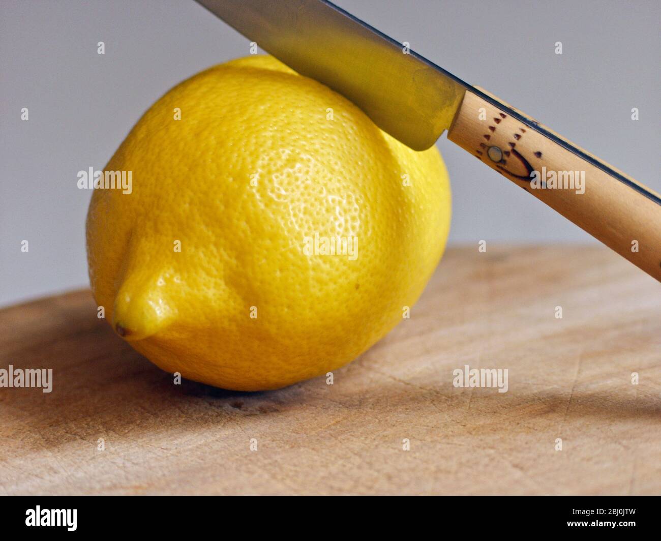 Limone fresco intero con coltello sul tagliere - Foto Stock