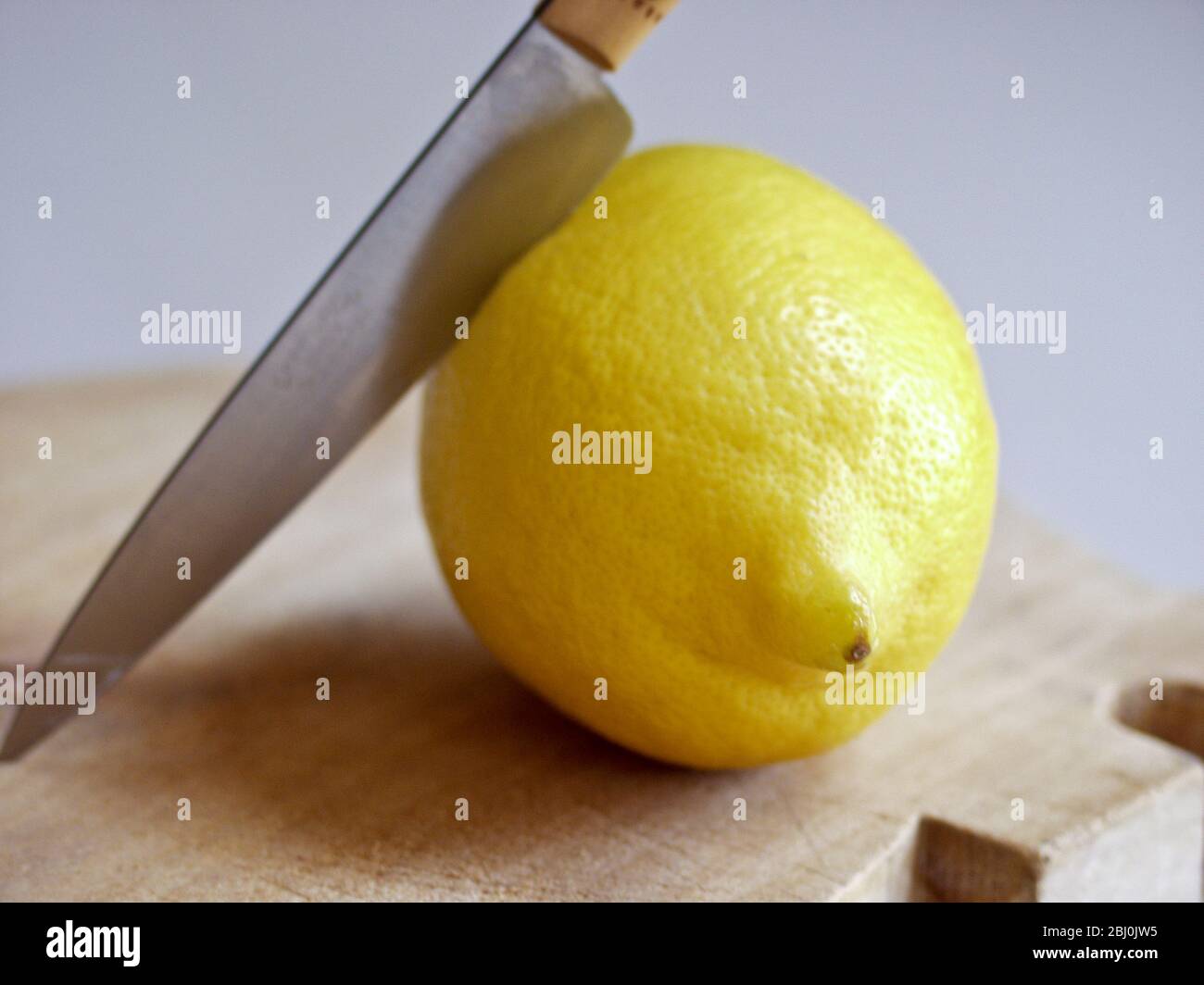 Limone fresco intero con coltello sul tagliere - Foto Stock