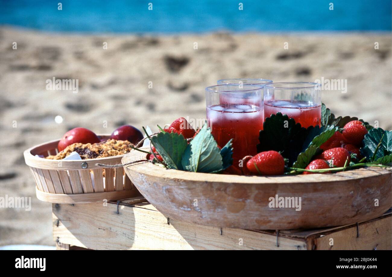 Succo di fragole in bicchieri alti con ghiaccio sul vassoio decorato con fragole e foglie di fragole - Foto Stock