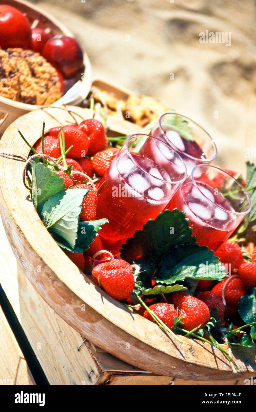 Succo di fragole in bicchieri alti con ghiaccio sul vassoio decorato con fragole e foglie di fragole - Foto Stock
