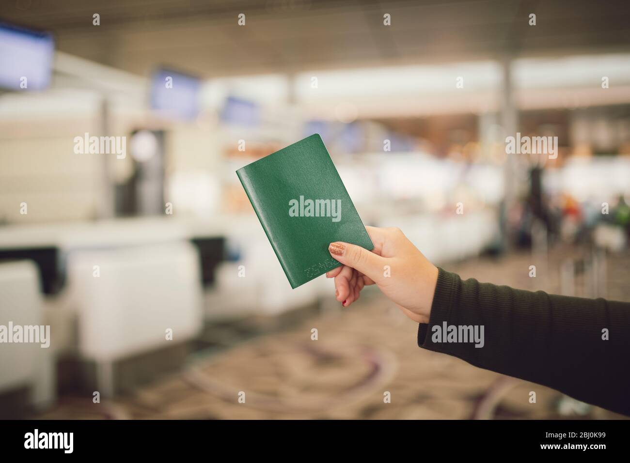 Un primo piano di una donna con un passaporto nella zona dell'aeroporto in attesa di check-in Foto Stock
