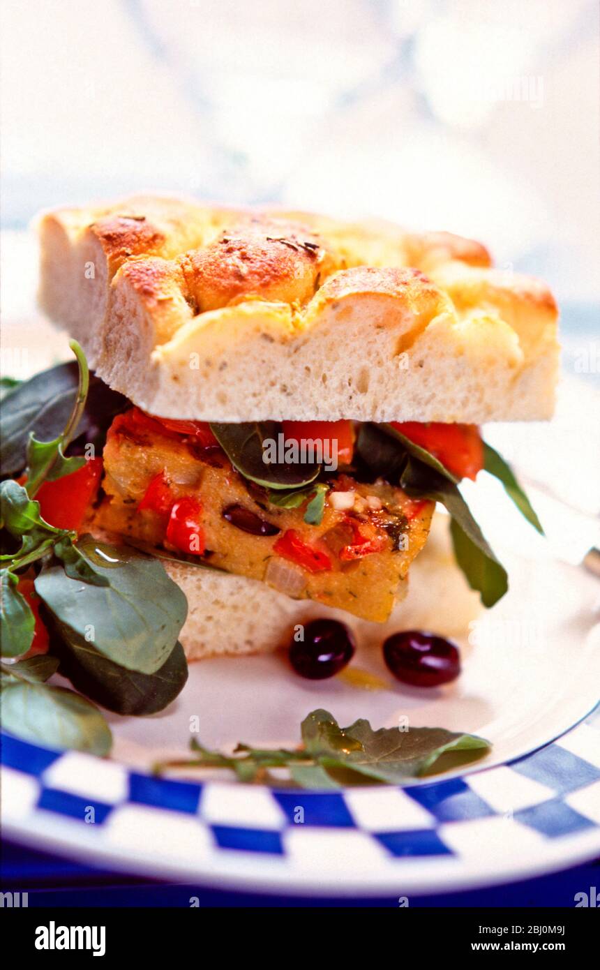 Sandwich di frittata spagnola in focaccia con insalata di rucola e olive nere - Foto Stock