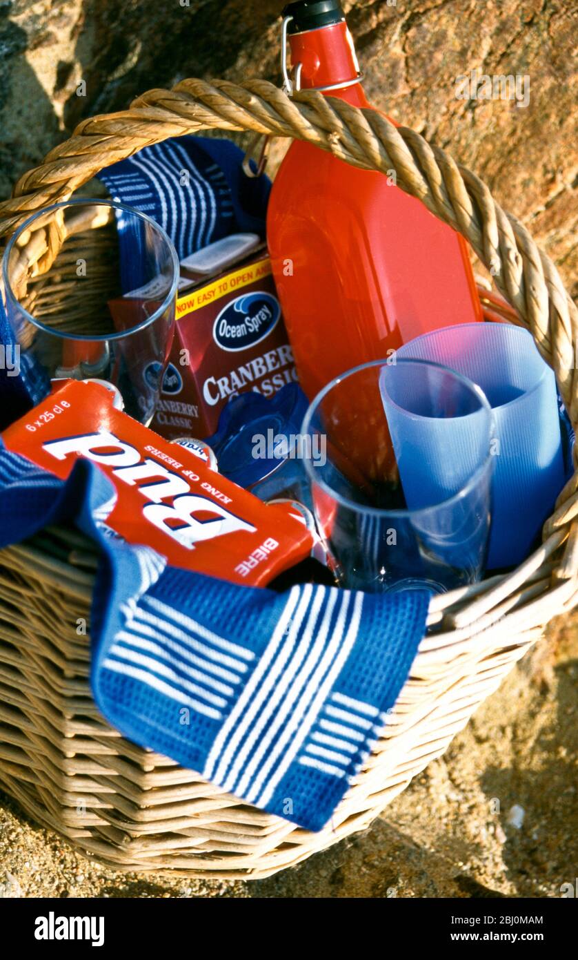 Cestino da picnic sulla spiaggia di sabbia con bevande e bicchieri - Foto Stock