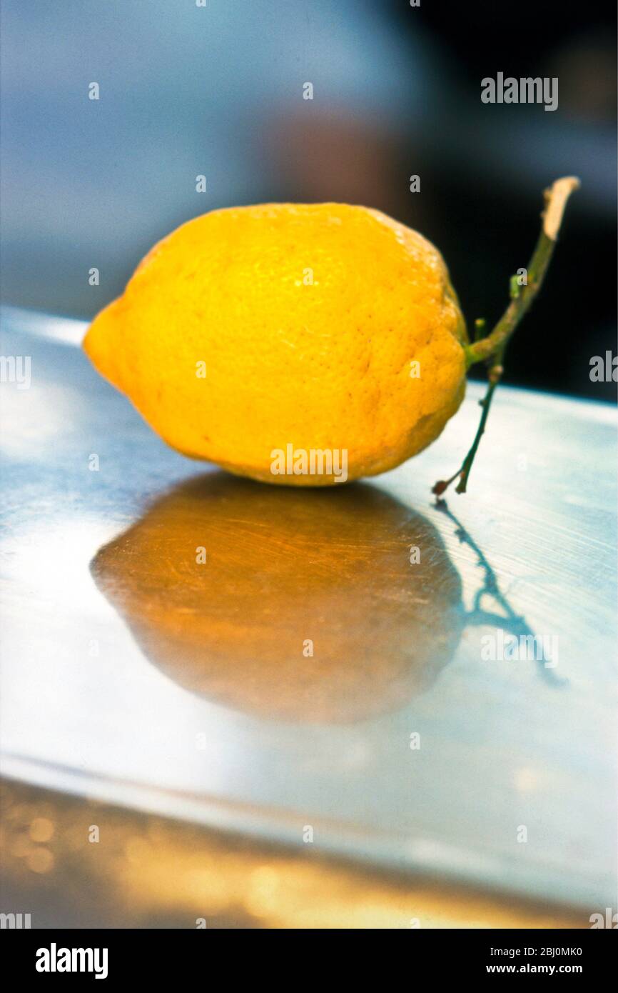 Singolo limone giallo su banco in acciaio inox - Foto Stock