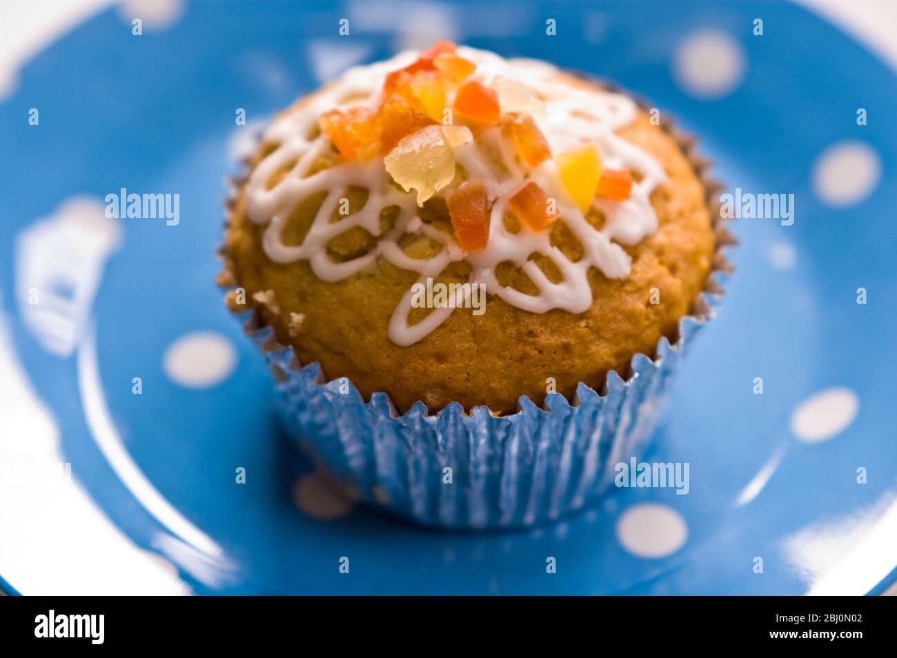 Muffin decorato con glassa squiggly e buccia candita su piatto blu spotted - Foto Stock