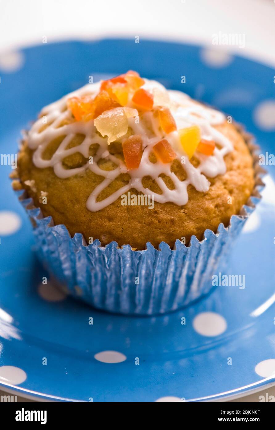 Muffin decorato con glassa squiggly e buccia candita su piatto blu spotted - Foto Stock