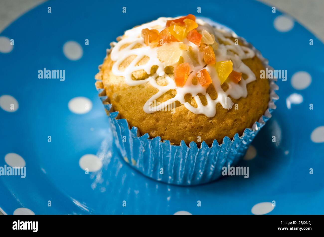 Muffin decorato con glassa squiggly e buccia candita su piatto blu spotted - Foto Stock