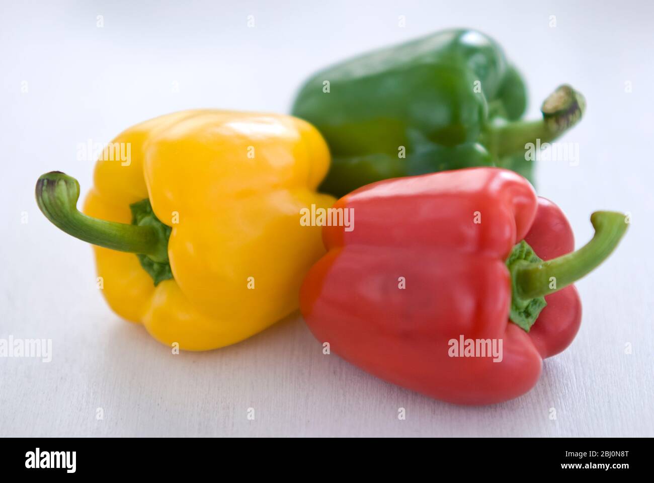 Tre peperoni dolci lucenti, rossi, verdi e gialli - Foto Stock