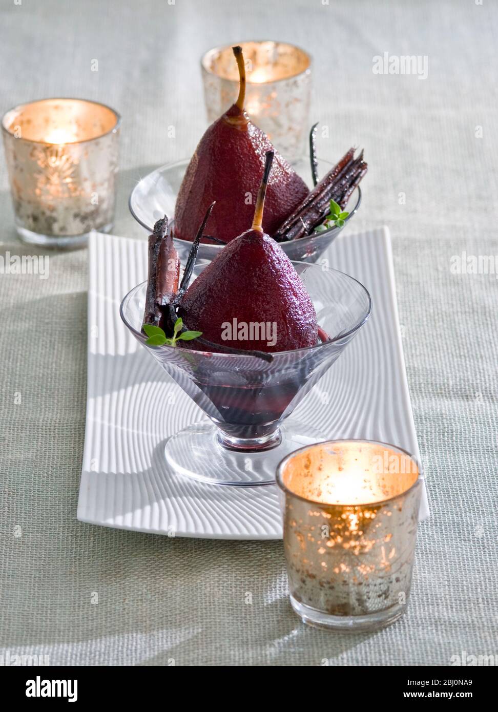 Pere in camicia nel vino rosso con tealights in ambiente party - Foto Stock