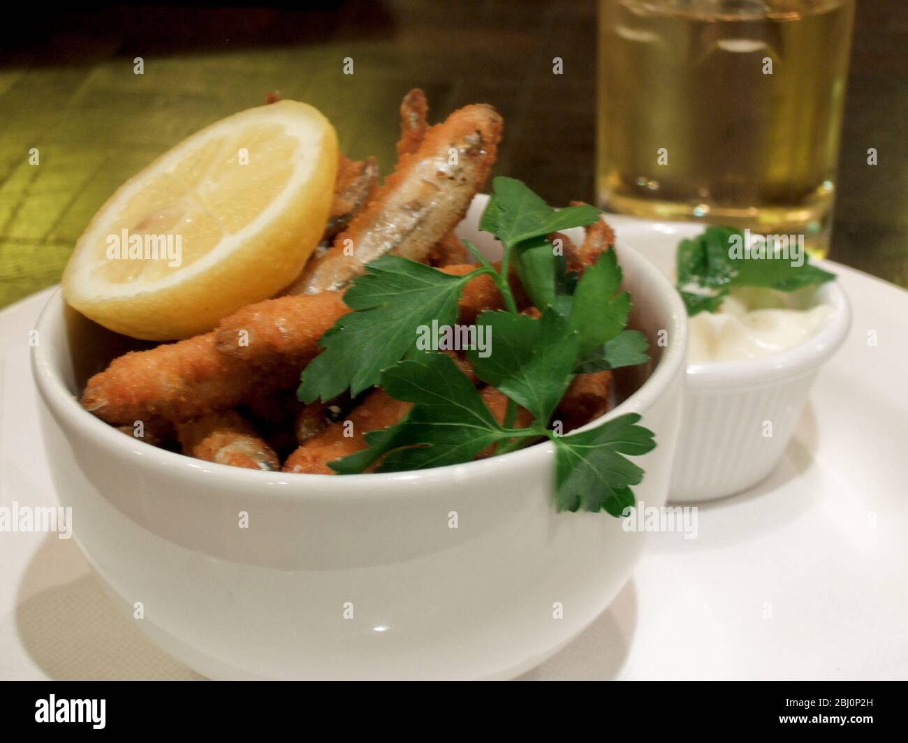 Whitebait fritto profondo, con cuneo di limone e maionese, guarnito con prezzemolo piatto. - Foto Stock