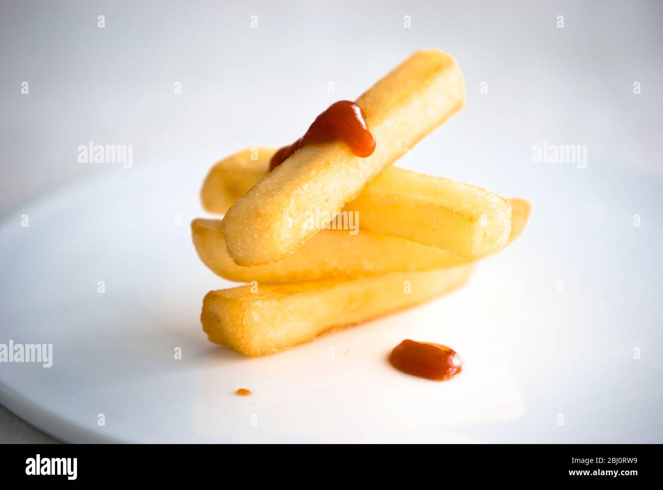 Pile accuratamente equilibrate di quattro patatine con gocce di ketchup di pomodoro - Foto Stock