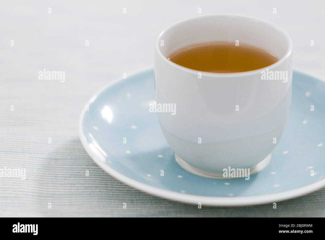 Calmante tazza di erbe o tè cinese in porcellana fine tazza senza manico su piattino blu e bianco macchiato - Foto Stock